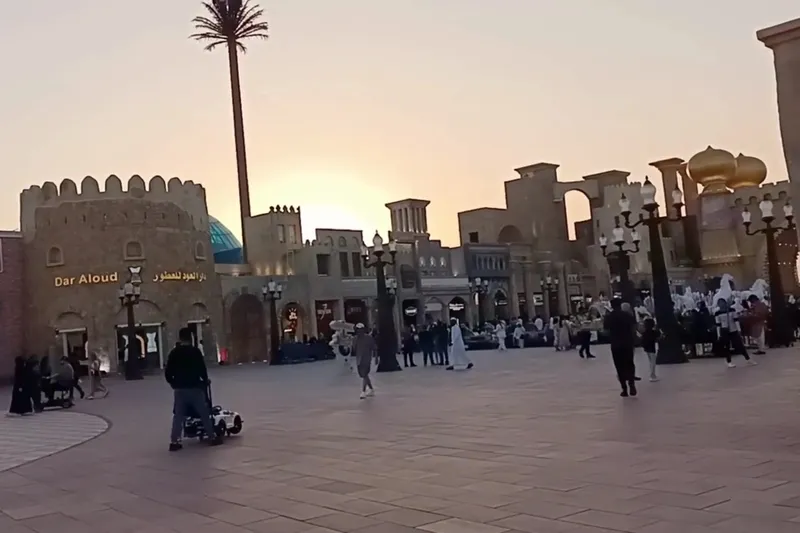 Вид на центральную площадь Global Village с архитектурой в ближневосточном стиле в лучах заходящего солнца.