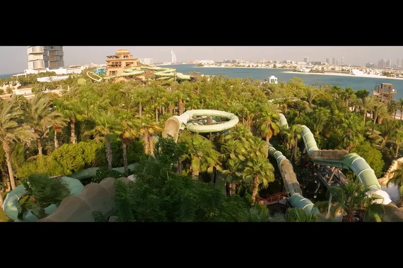 Панорамный вид на аквапарк Aquaventure с водными горками среди пальм в Дубае