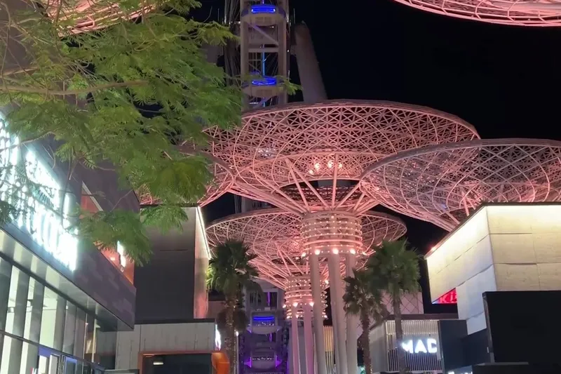 Вечерняя прогулочная зона Bluewaters с подсвеченными навесами и видами на Ain Dubai