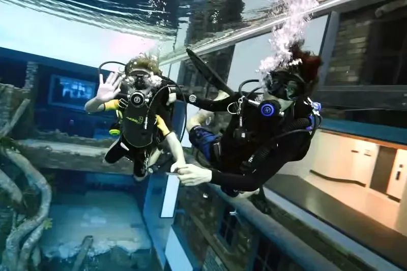 Дайверы исследуют затонувший город в бассейне Deep Dive Dubai в Дубае