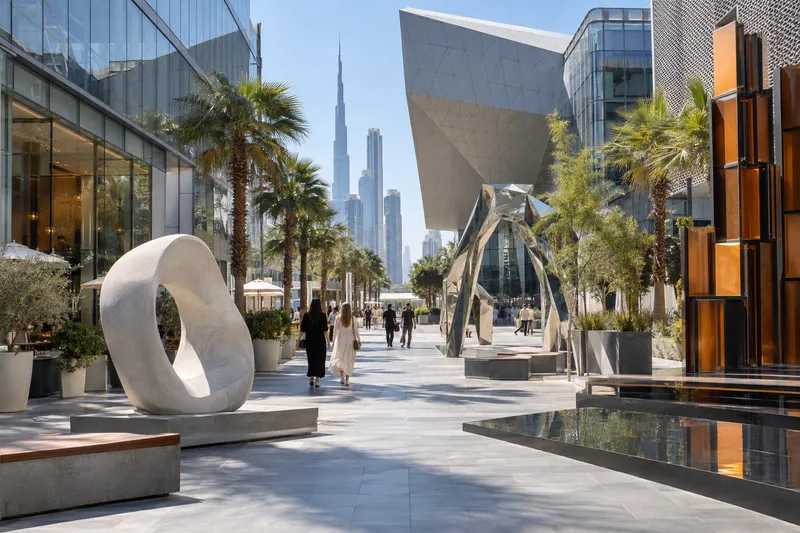 Современная пешеходная площадь Dubai Design District с геометричными зданиями и арт-объектами