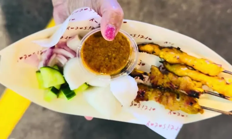 Еда на шпажках с соусом и овощами на ярмарке Global Village