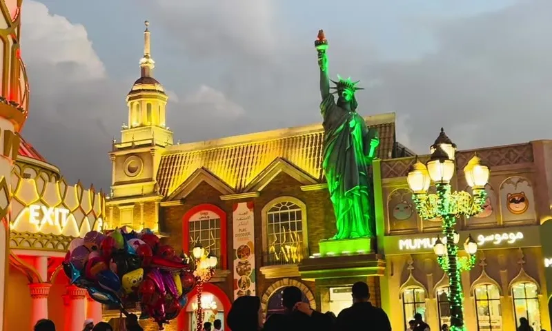 Вечерний Global Village в Дубае с павильонами разных стран и копией Статуи Свободы
