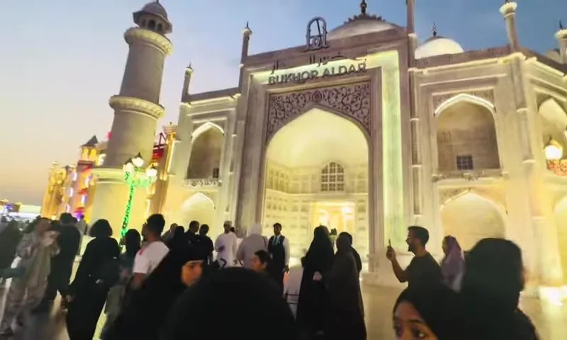 Посетители Global Village у ярко освещённого павильона в вечернее время