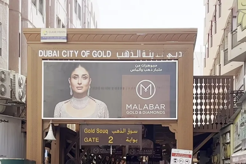 Деревянная входная арка «Dubai City of Gold» у вторых ворот рынка с рекламой ювелирных изделий Malabar.
