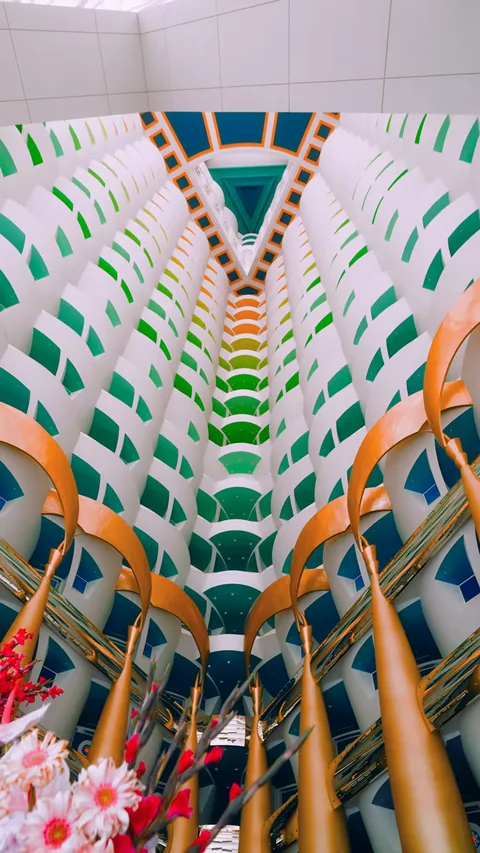 Атриум Burj Al Arab снизу вверх: золотые колонны и цветные ярусы балконов