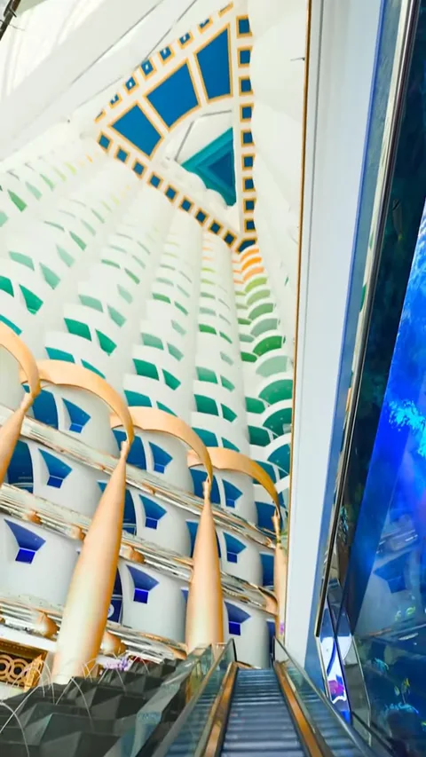 Эскалатор в лобби Burj Al Arab вдоль синей стены-аквариума