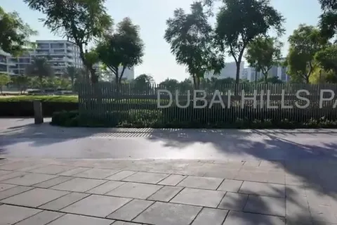 Вход в парк Dubai Hills с дорожкой, деревьями и жилыми зданиями на заднем плане