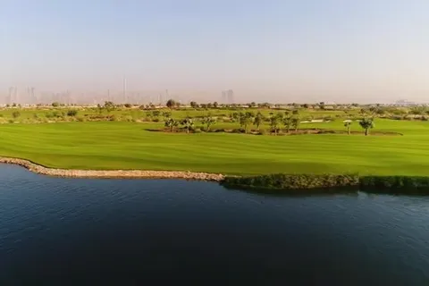 Зелёный парк у воды на фоне городской панорамы Дубая