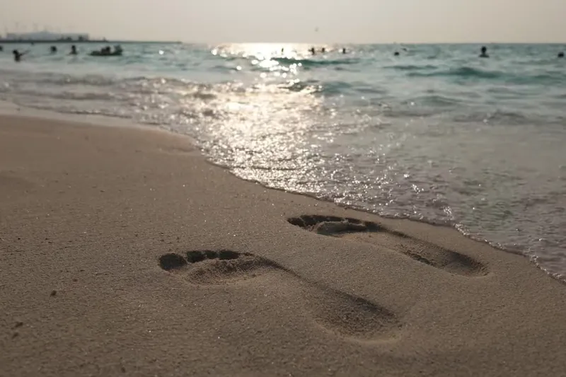Следы на песке у кромки воды на пляже Kite Beach в Дубае