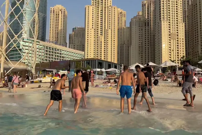 Отдыхающие на общественном пляже JBR в Дубае на фоне прибрежных высоток