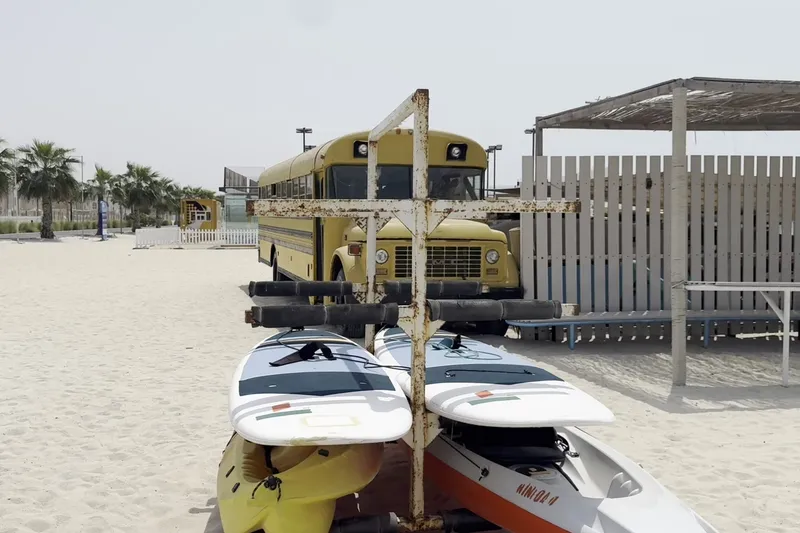Пляжная зона Kite Beach с досками для водных развлечений и автобусом на заднем плане