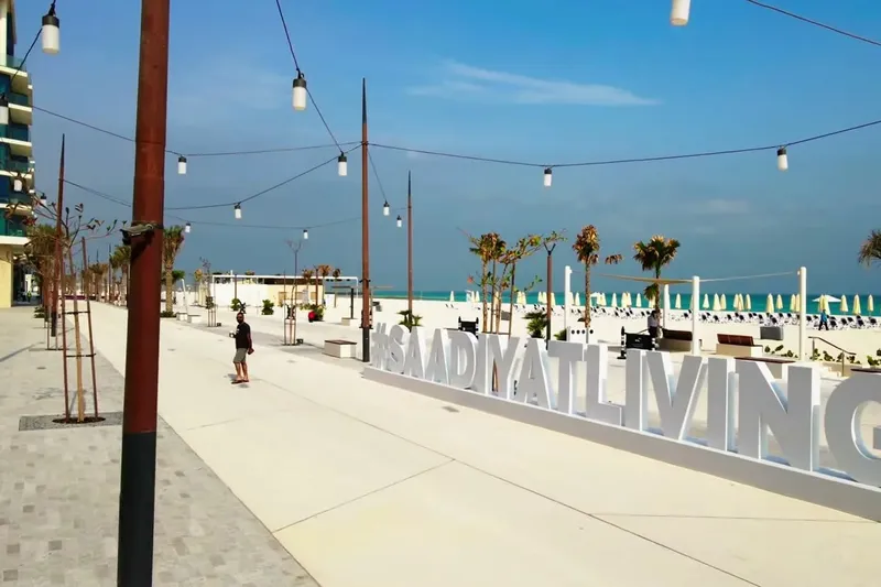 Пляж острова Саадият с бирюзовой водой, белым песком и надписью Saadiyat Living