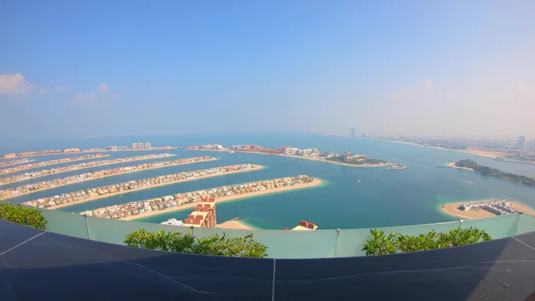 Вид на ветви острова Палм-Джумейра и бирюзовые воды Персидского залива с большой высоты Aura Skypool.
