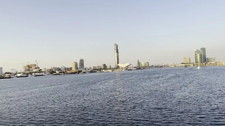 Панорамный вид на горизонт Дубая и башню Бурдж-Халифа с набережной Крик Харбор в ясную погоду.