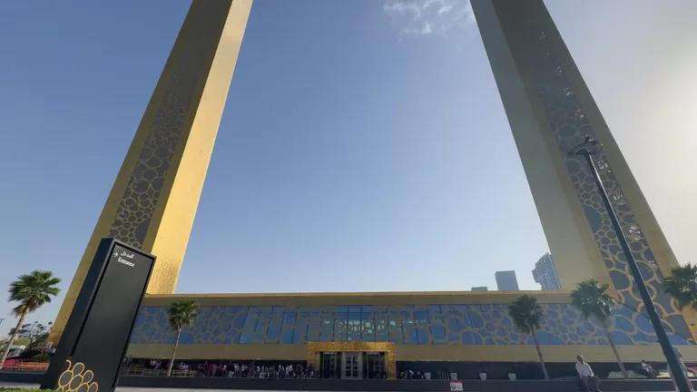 Вид снизу на две золотые башни и соединяющий их мост на фоне ясного голубого неба.