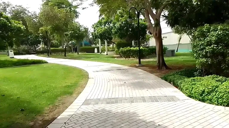 Извилистая пешеходная дорожка, проходящая через ухоженные зеленые газоны и насаждения в парке Забиль.