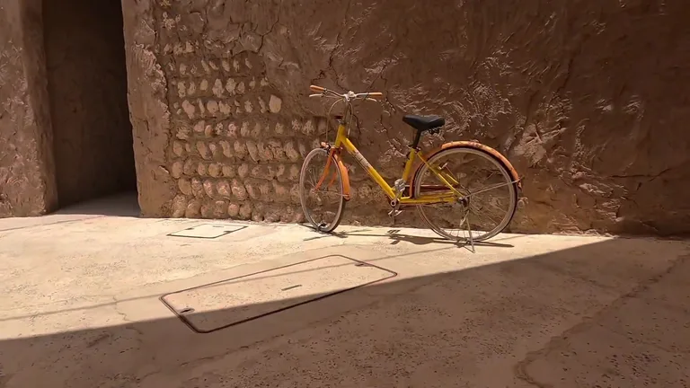 Желтый велосипед, припаркованный у каменной стены с фактурной отделкой в историческом районе Al Seef.