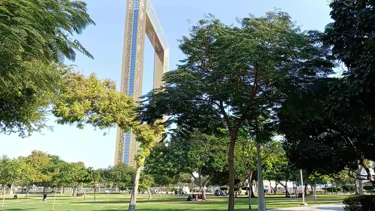 Массивная золотая конструкция Рамки Дубая возвышается над деревьями на территории парка Забиль.