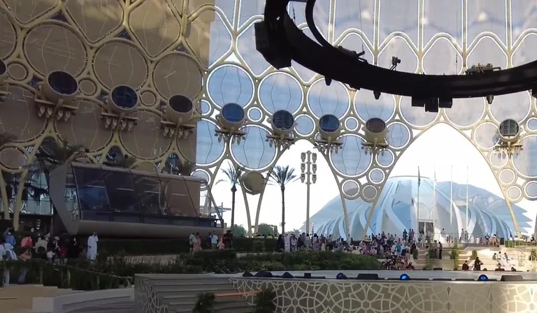 View through an arch of Al Wasl Plaza towards a distant pavilion.