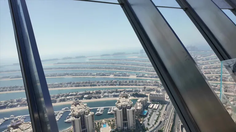 Вид через панорамное остекление на рукотворный ландшафт острова Пальма Джумейра и воды Персидского залива.