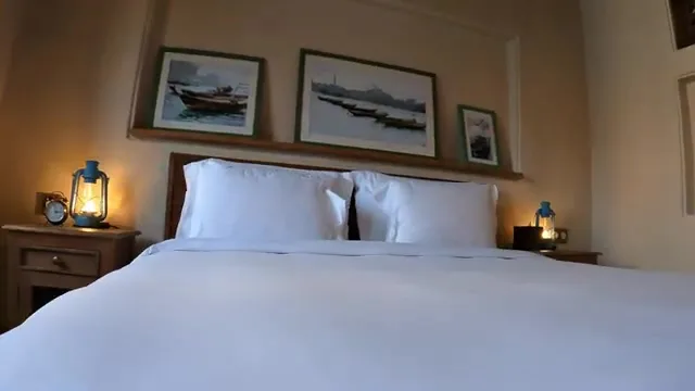 Интерьер гостиничного номера в традиционном стиле с винтажными фонарями и эскизами лодок доу над кроватью.