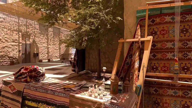 Традиционные ковры и текстиль с местными орнаментами, выставленные на продажу на открытом рынке в районе Al Seef.