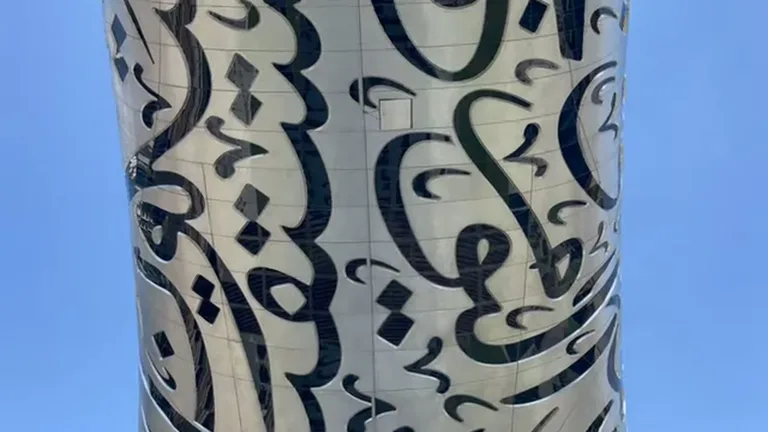 Серебристая обшивка Музея Будущего крупным планом с узорами арабского письма