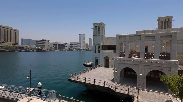 Традиционные здания с ветряными башнями на набережной залива Дубай-Крик и современные постройки на противоположном берегу.