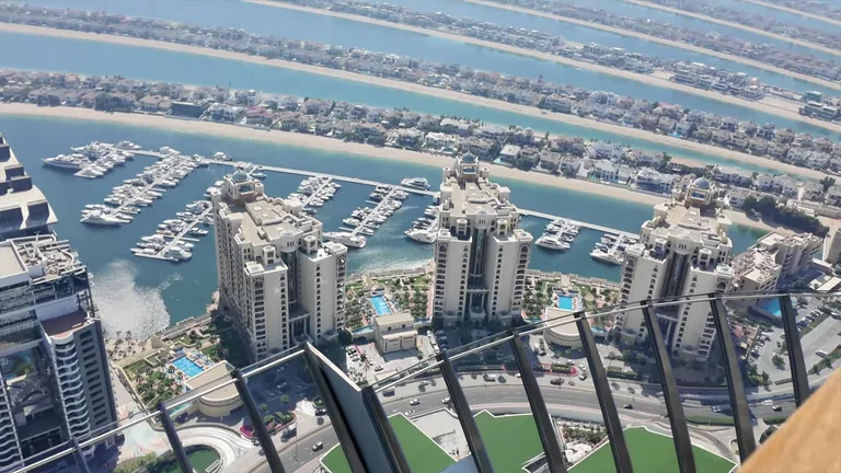 Вид сверху на жилые небоскребы и пристань для яхт у основания искусственного острова Пальма Джумейра.