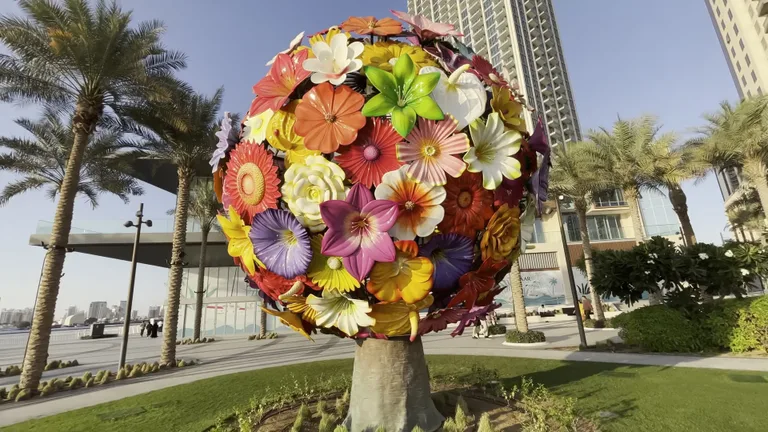 Сферическая арт-инсталляция из разноцветных металлических цветов, расположенная на пешеходной набережной района Dubai Creek Harbour.