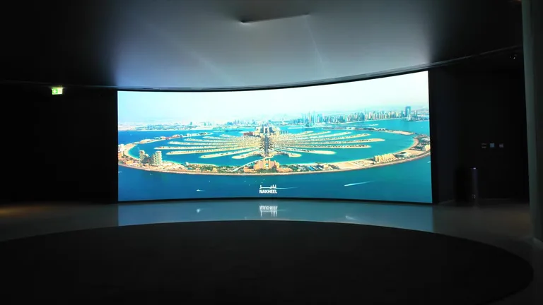 Изображение острова Пальма Джумейра на большом изогнутом цифровом экране в выставочной зоне перед подъемом.