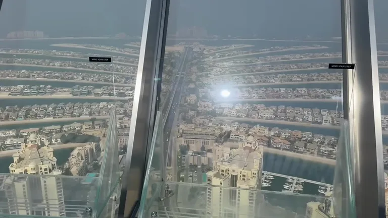 Вид на жилые виллы и ветви пальмы через стеклянный пол смотровой площадки The View at The Palm.