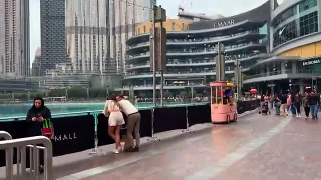 Прогулочная набережная у озера с розовым киоском и видом на современные небоскребы центра Дубая.