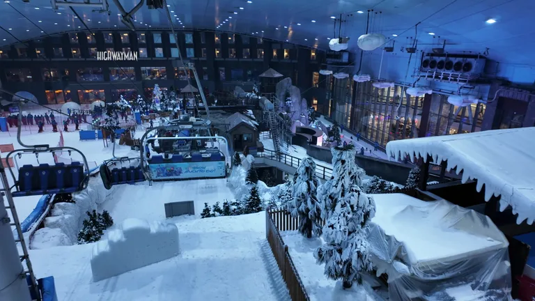 Тематическая зона альпийской деревни внутри комплекса Ski Dubai с заснеженными крышами и искусственными елками для отдыха посетителей.