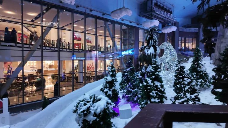 Заснеженные склоны комплекса Ski Dubai, отделенные стеклянными перегородками от торговых галерей с посетителями торгового центра.