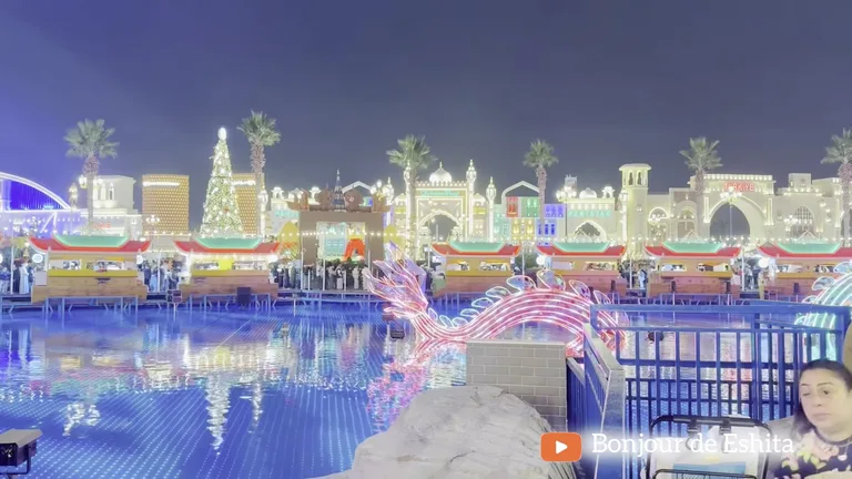 Светящаяся розовая скульптура дракона в водном канале, отражающем разноцветные огни окружающих павильонов.