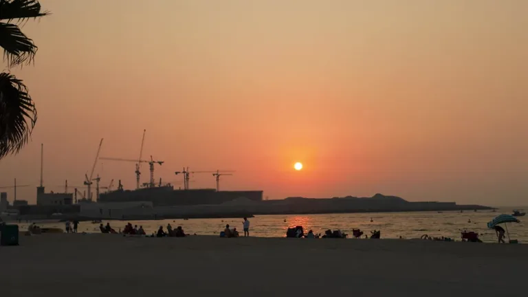 Отдыхающие на пляже Kite Beach, играющие в пляжный теннис и волейбол рядом с кромкой воды.