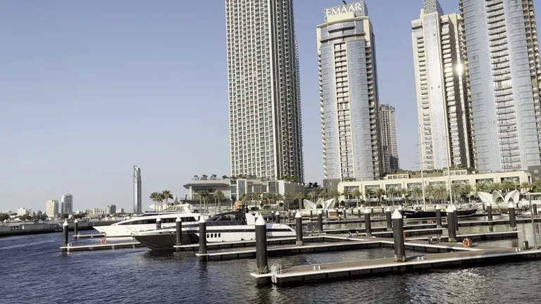 Пристань для яхт в районе Dubai Creek Harbour с пришвартованными судами на фоне современных стеклянных небоскребов.
