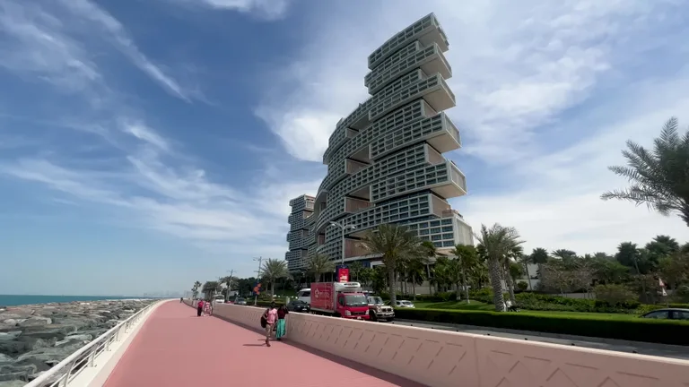 Современная модульная архитектура отеля Atlantis The Royal и розовая пешеходная дорожка на фоне ясного неба.