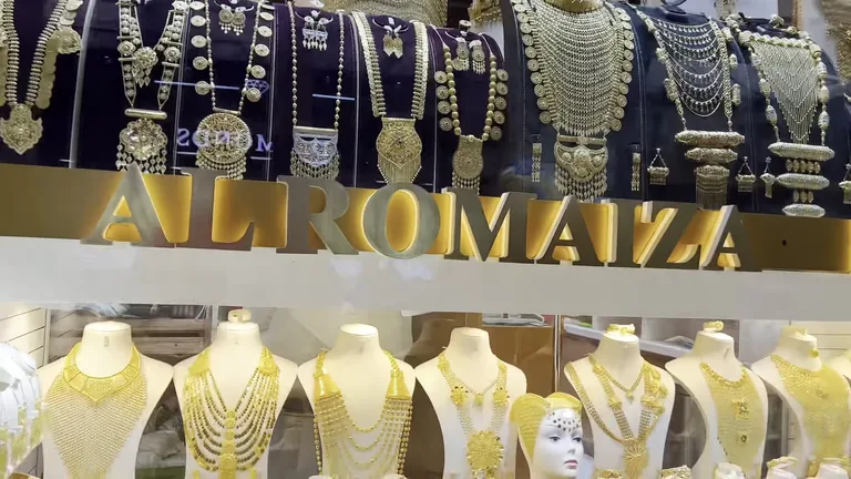 Витрина магазина Al Romaizan, где на манекенах представлены массивные золотые ожерелья и свадебные комплекты украшений.