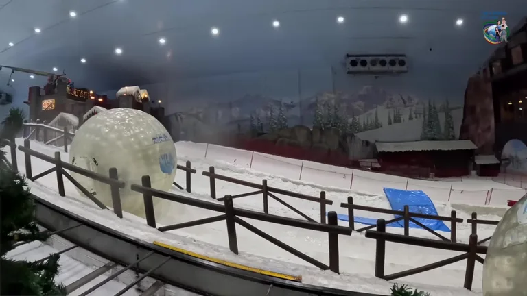 Большой прозрачный шар зорб катится вниз по заснеженного склону в крытом комплексе Ski Dubai.