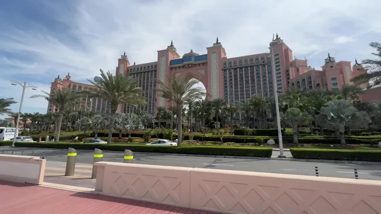 Фасад курортного комплекса Atlantis The Palm с его узнаваемой центральной аркой, розовыми башнями и пальмами.