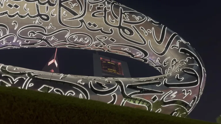 Ночная подсветка фасада музея, где окна в форме арабской каллиграфии светятся белым цветом.