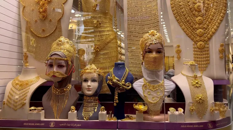 Традиционные золотые головные уборы и лицевые вуали для свадебных церемоний, выставленные на манекенах в витрине.