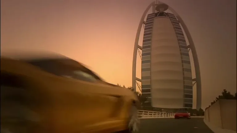 Вид на знаменитый отель Бурдж-аль-Араб на закате и желтый спортивный автомобиль, въезжающий на мост.