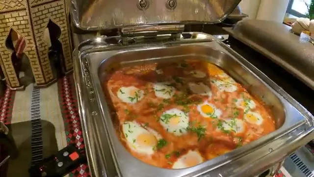 Традиционная шакшука с яйцами-пашот в томатно-перечном соусе, украшенная свежей зеленью, на шведском столе в Al Seef.