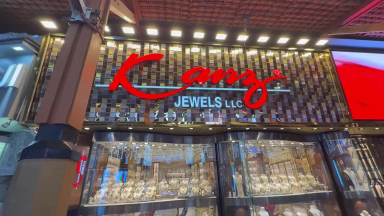 Фасад ювелирного магазина Kanz Jewels с яркой вывеской и витриной, заполненной сотнями золотых украшений.