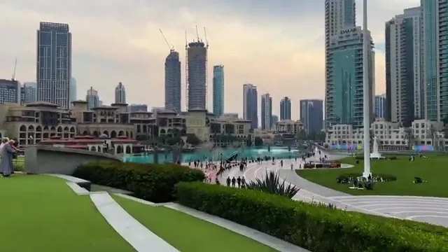 Обзорный вид на набережную у фонтанов, окруженную зданиями в традиционном и современном стилях.